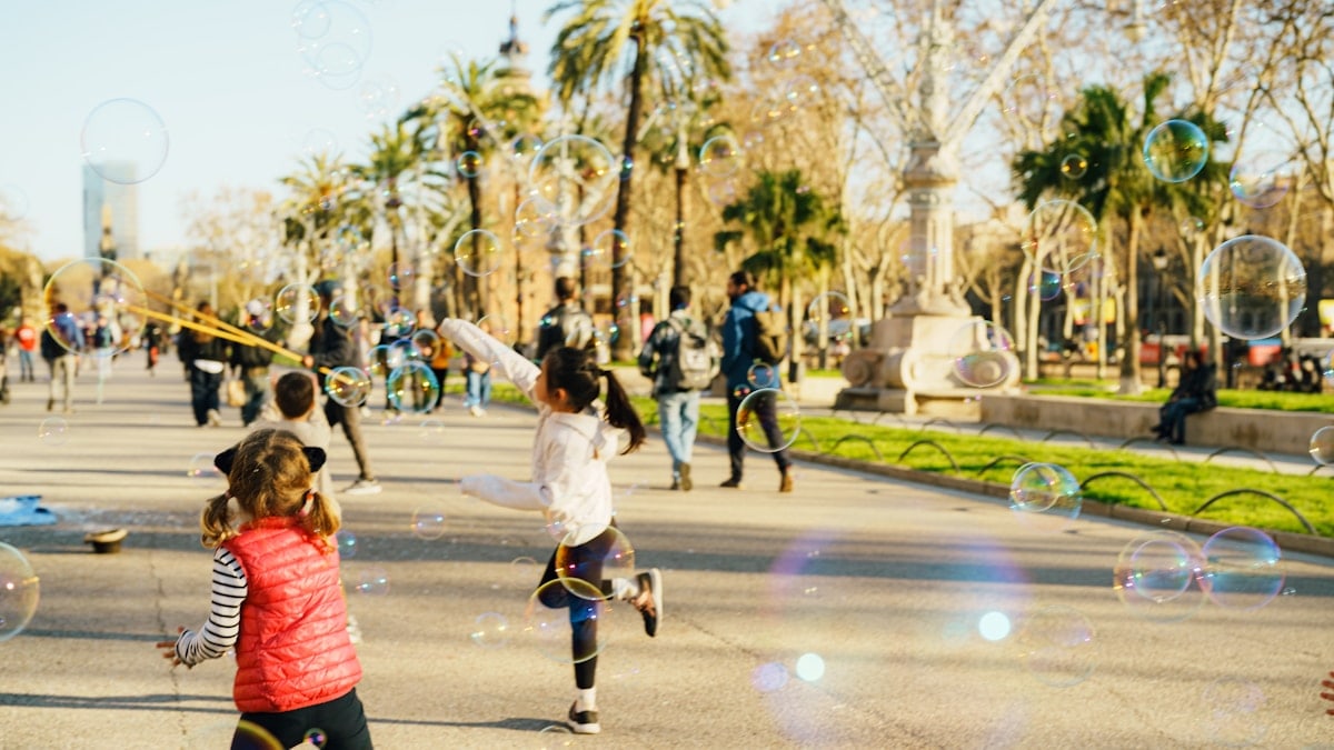 Children chasing bubbles in a sunny park
